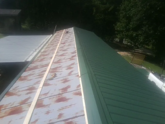 Old rusted panels beside newly installed green metal roofing — Wind Damage Roof Repair by Roofing Brothers in Wadsworth